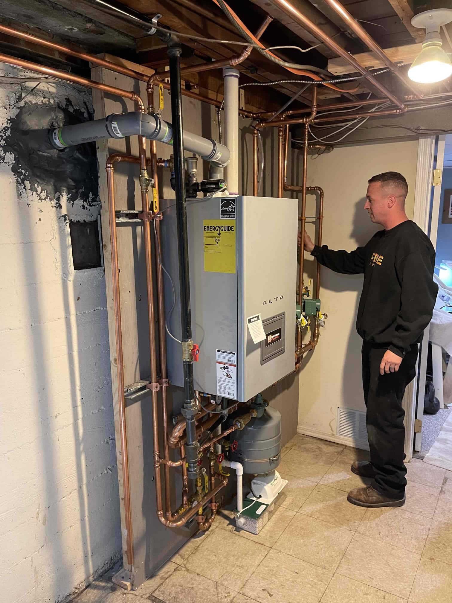 Pride Services technician working on a water heater in the basement in Rockville Centre, NY