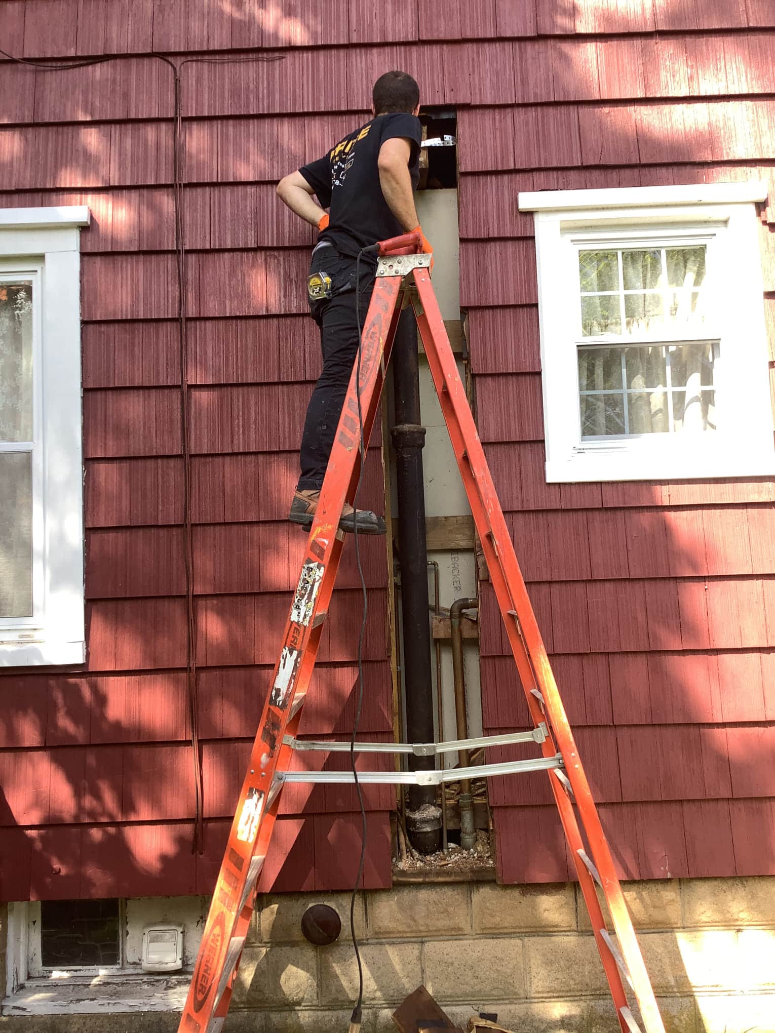 Pride Services technician working on piping outside on a ladder in Rockville Centre, NY